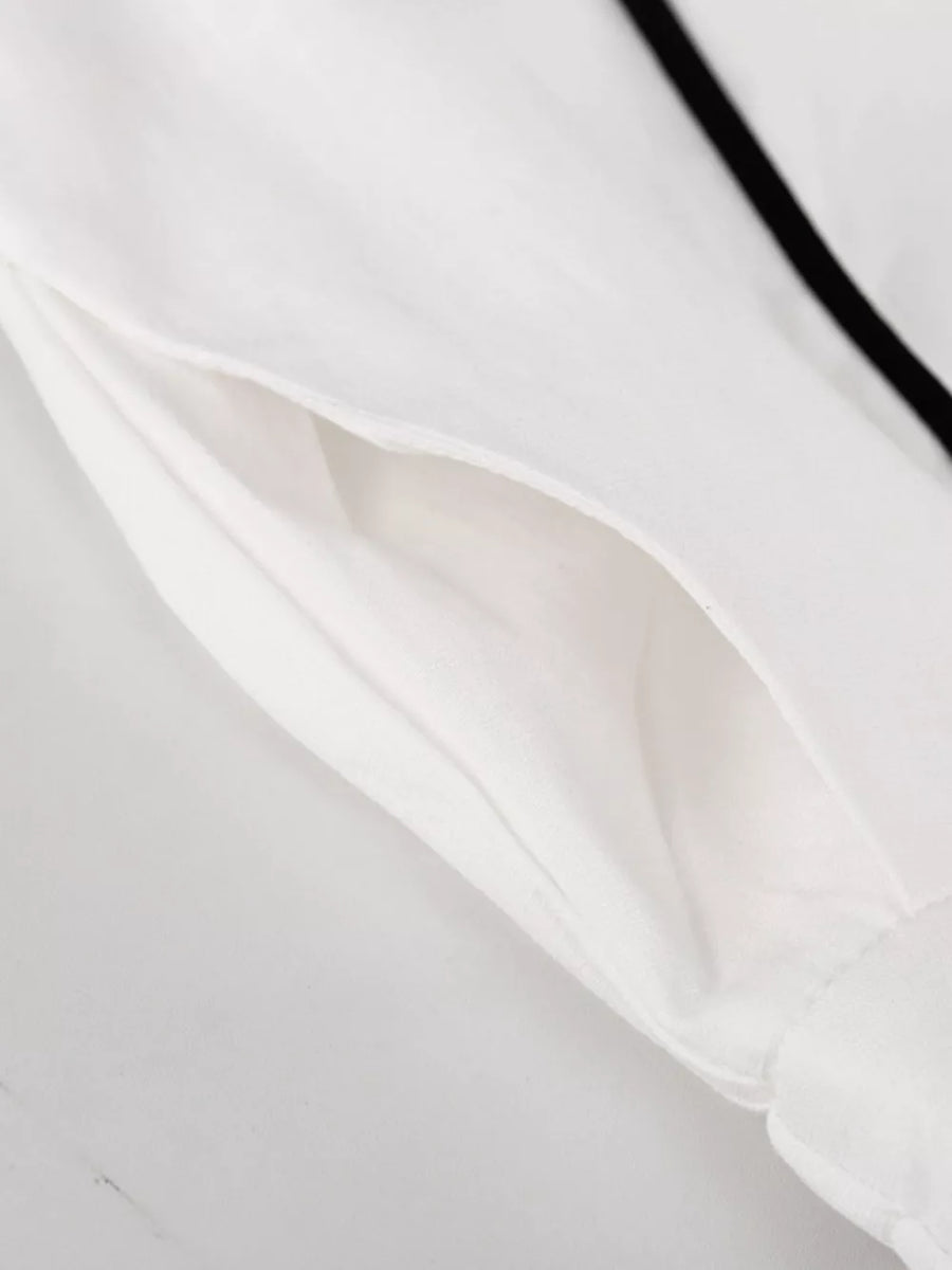 White shirt with black piping detail and a pocket