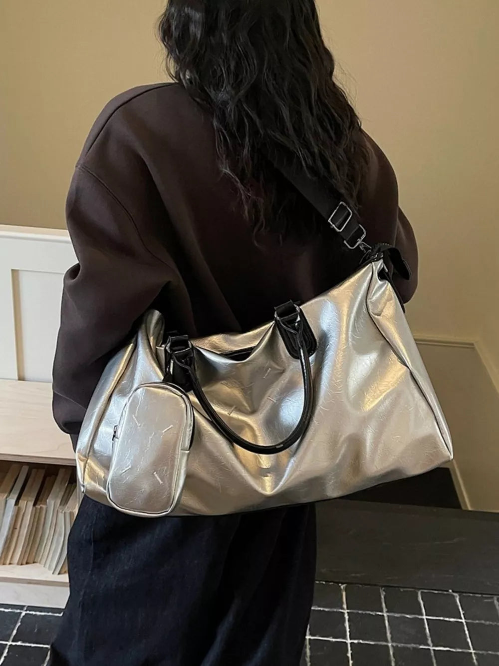 Sleek silver metallic large travel bag with adjustable strap and matching pouch.