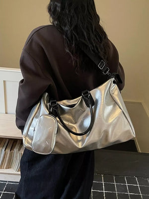 Sleek silver metallic large travel bag with adjustable strap and matching pouch.