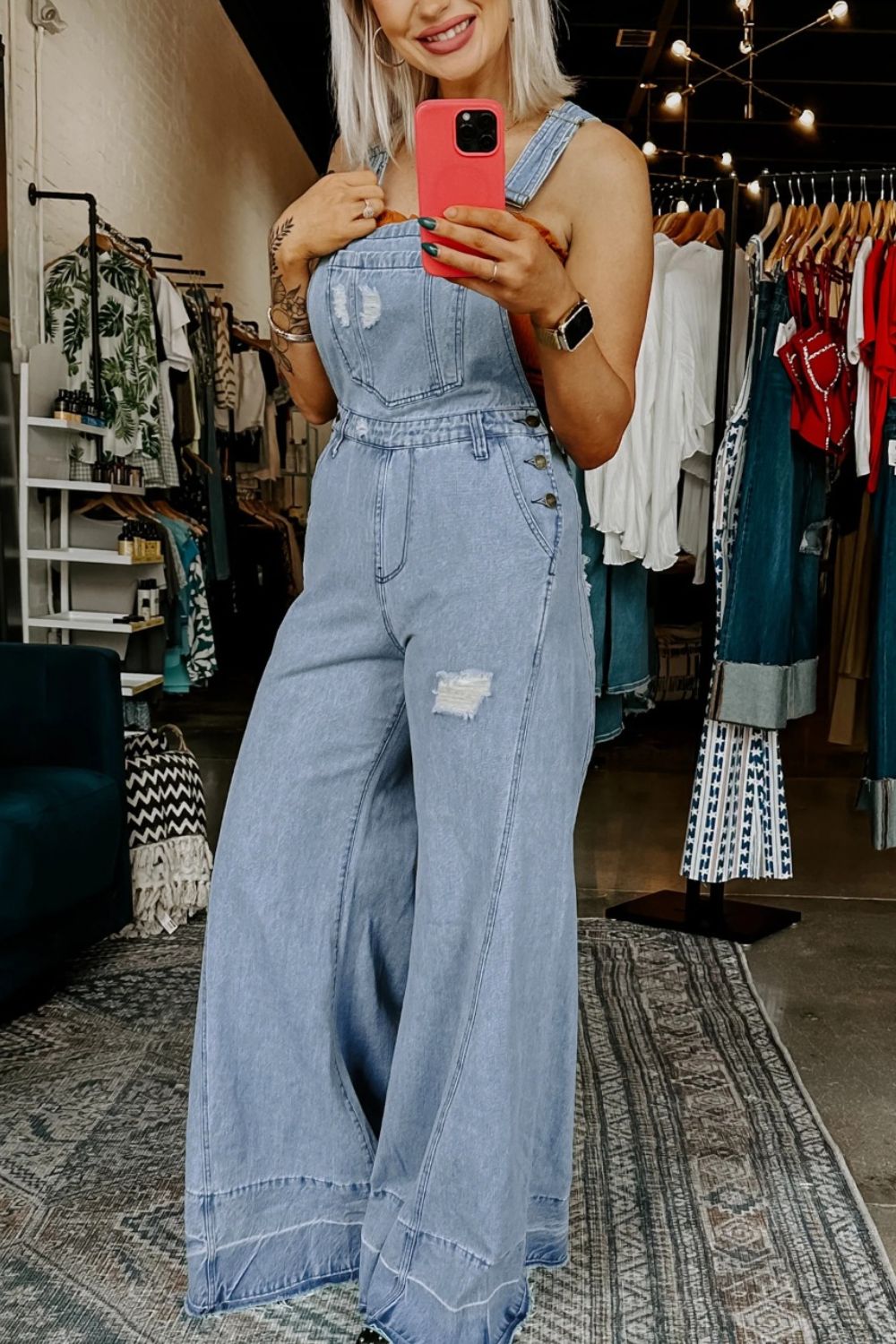 Distressed light wash denim overalls with wide legs and button details.