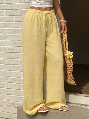 Yellow textured wide-leg pants with drawstring waist and relaxed fit.