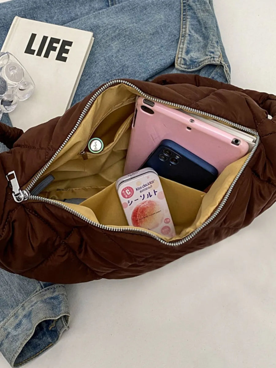 Quilted crossbody bag in brown with open interior showing phone, tablet, and small tin.