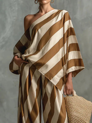 Brown and cream striped one-shoulder top with wide-leg pants, styled with a straw tote bag.