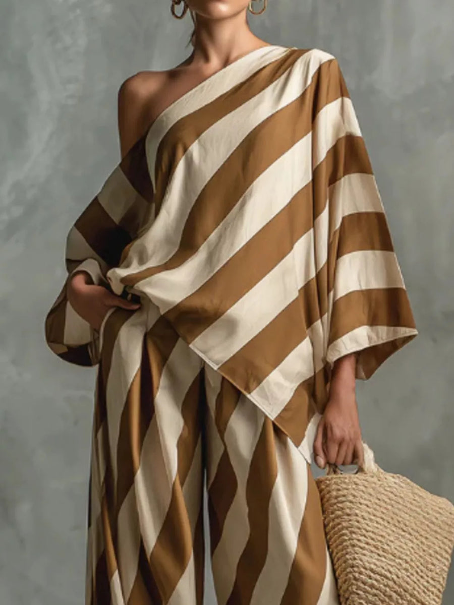 Brown and cream striped one-shoulder top with wide-leg pants, styled with a straw tote bag.