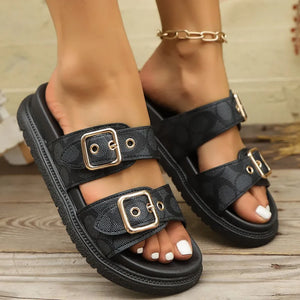 Black slide sandals with double buckle straps and logo pattern.