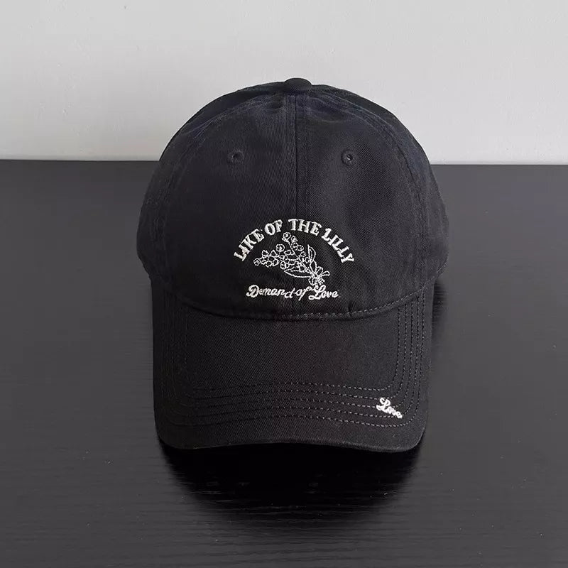 Black cotton cap with embroidered floral design and text.