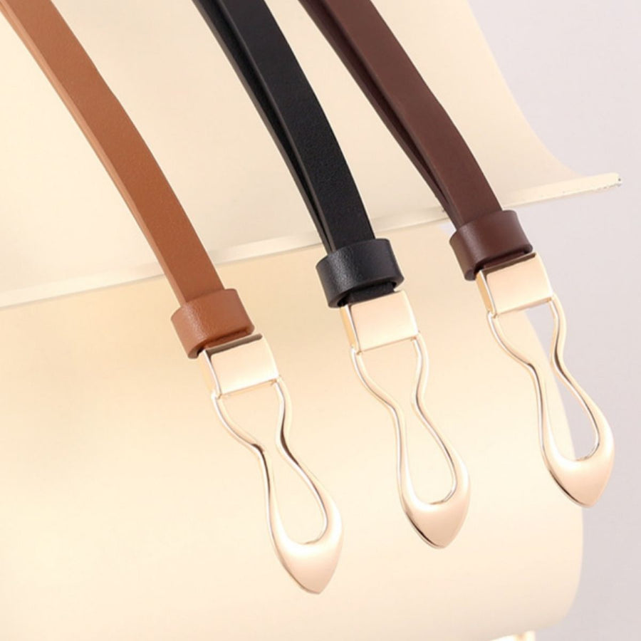 Elegant leather belts in brown, black, and caramel with interlocking gold buckles.