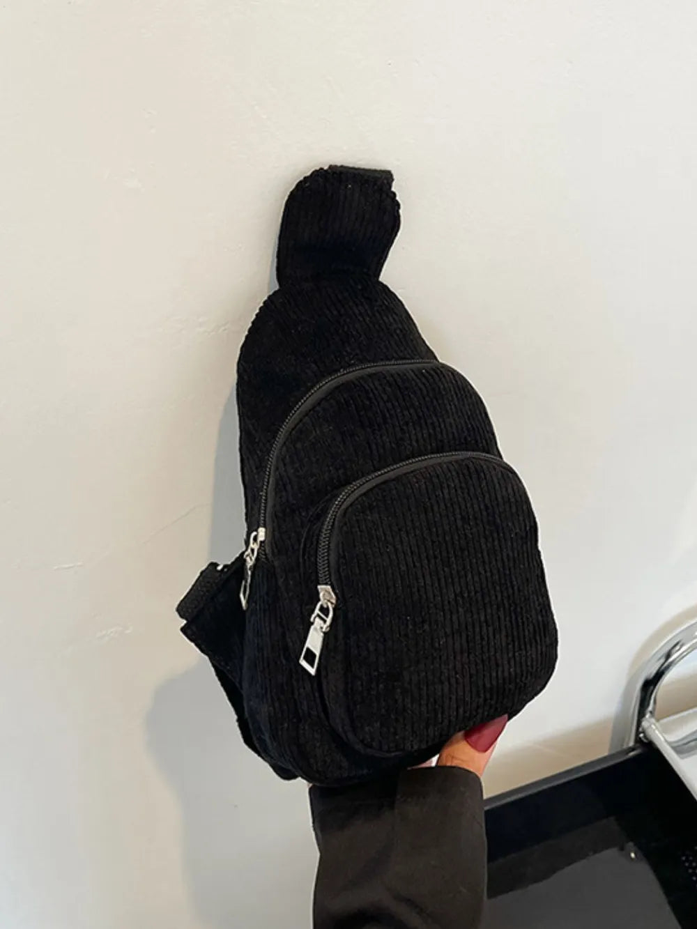 Black corduroy sling bag with zip pockets and adjustable strap