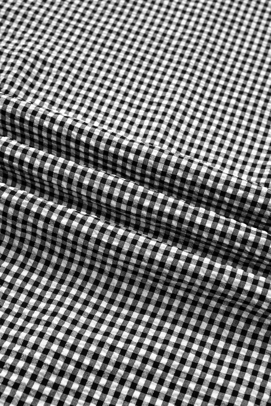Black and white gingham polyester shirt with ruffled sleeves and bow tie detail.