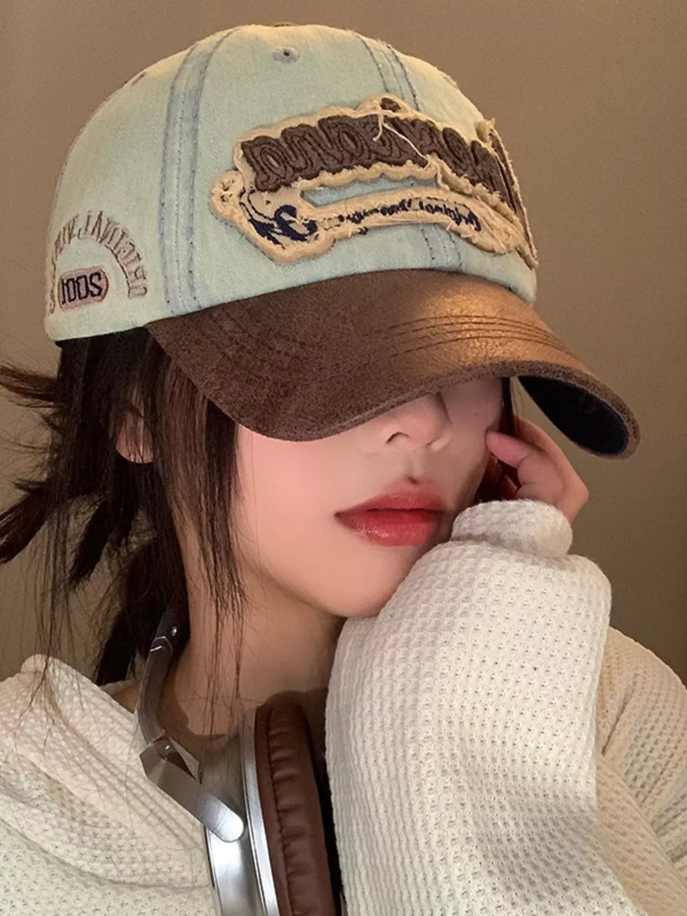 Distressed denim baseball cap in light cowboy blue with brown brim and embroidered logo.