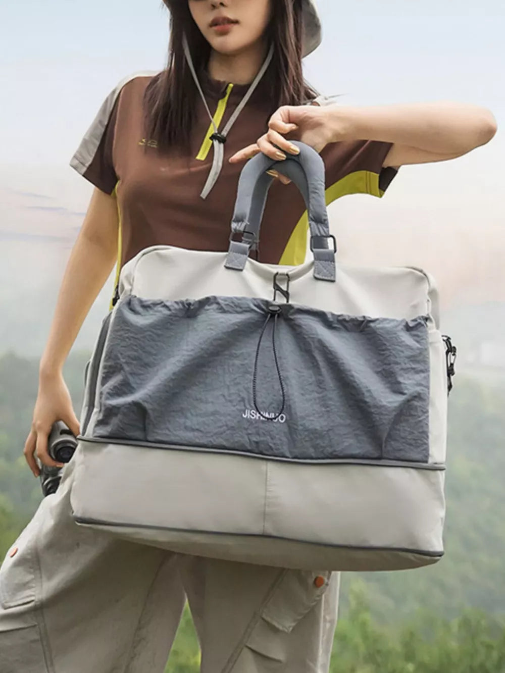 Crinkled nylon drawstring travel bag in gray and beige with top handles and a shoulder strap.