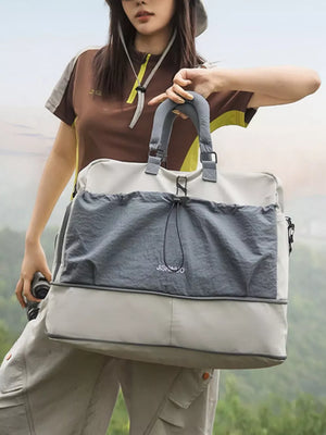 Crinkled nylon drawstring travel bag in gray and beige with top handles and a shoulder strap.