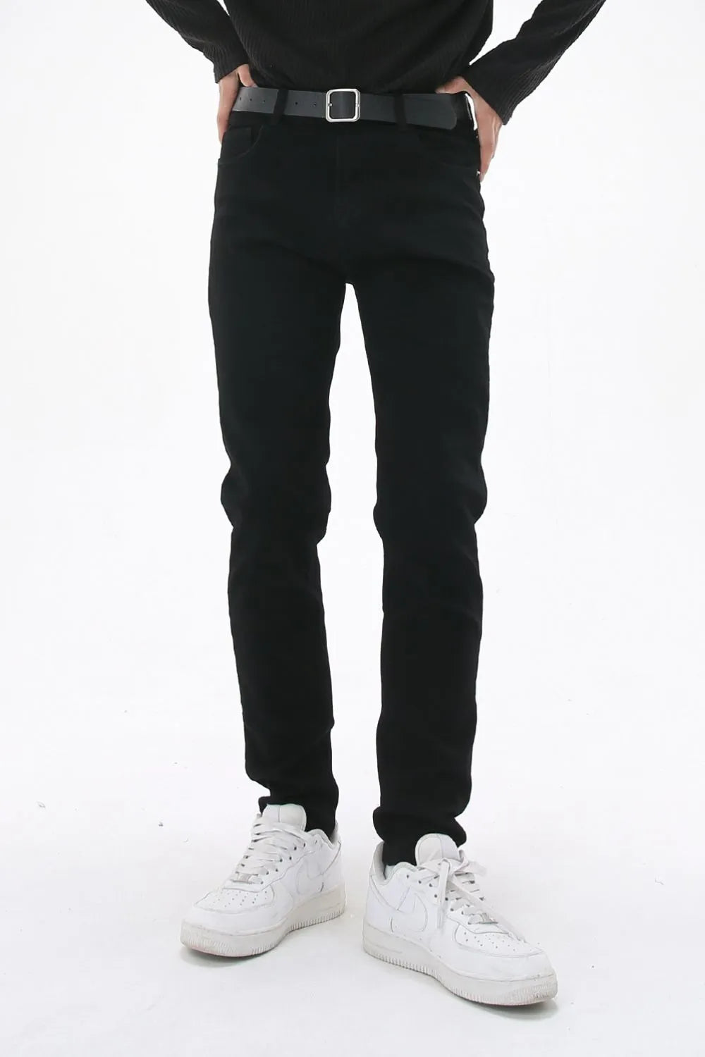 Black slim-fit stretch denim trousers with a black belt.