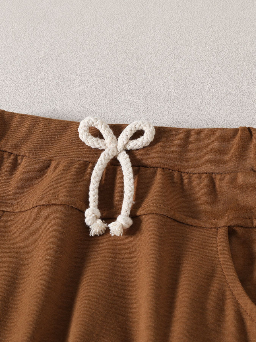 Light brown baby set shorts with drawstring waist and pocket detail.