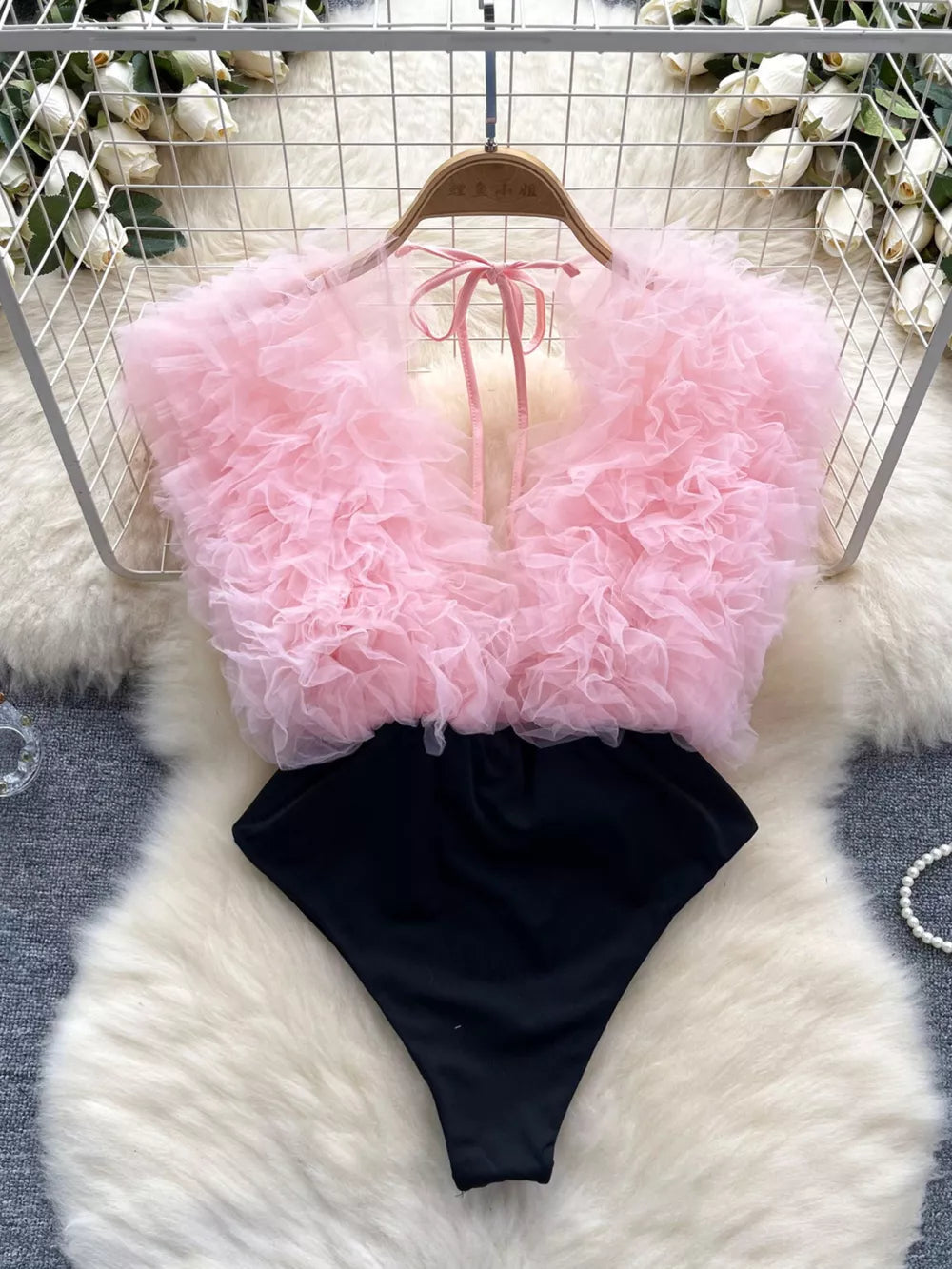 Pink ruffled V-neck bodysuit with black bottom and lace detail
