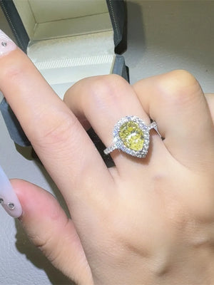 Yellow pear-cut moissanite ring with diamond halo and band.