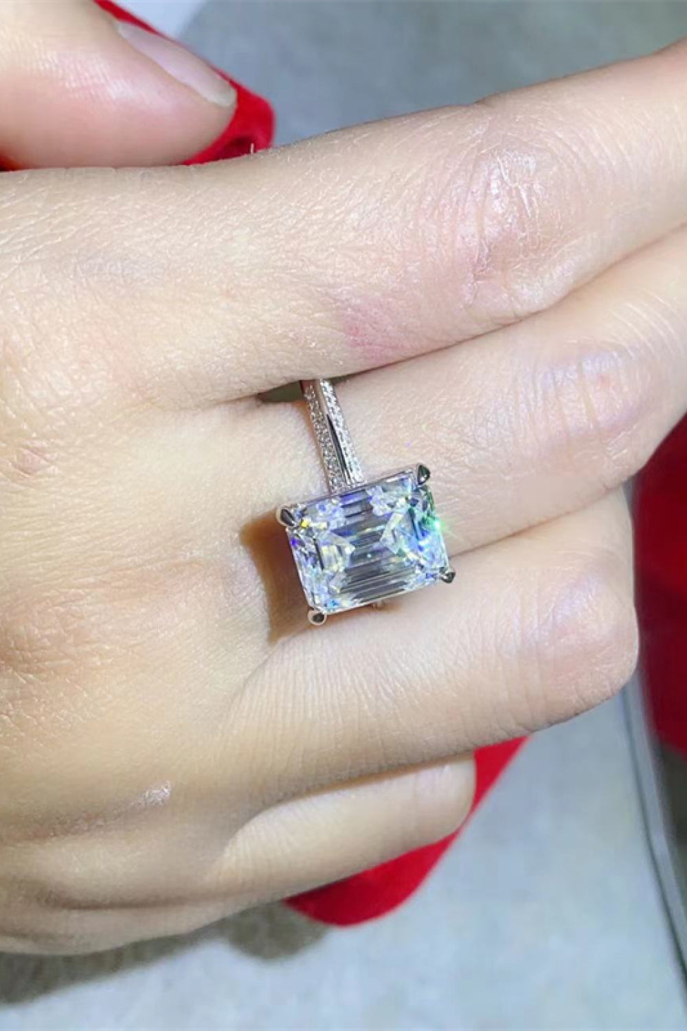 Platinum engagement ring with emerald cut solitaire diamond and pave band.