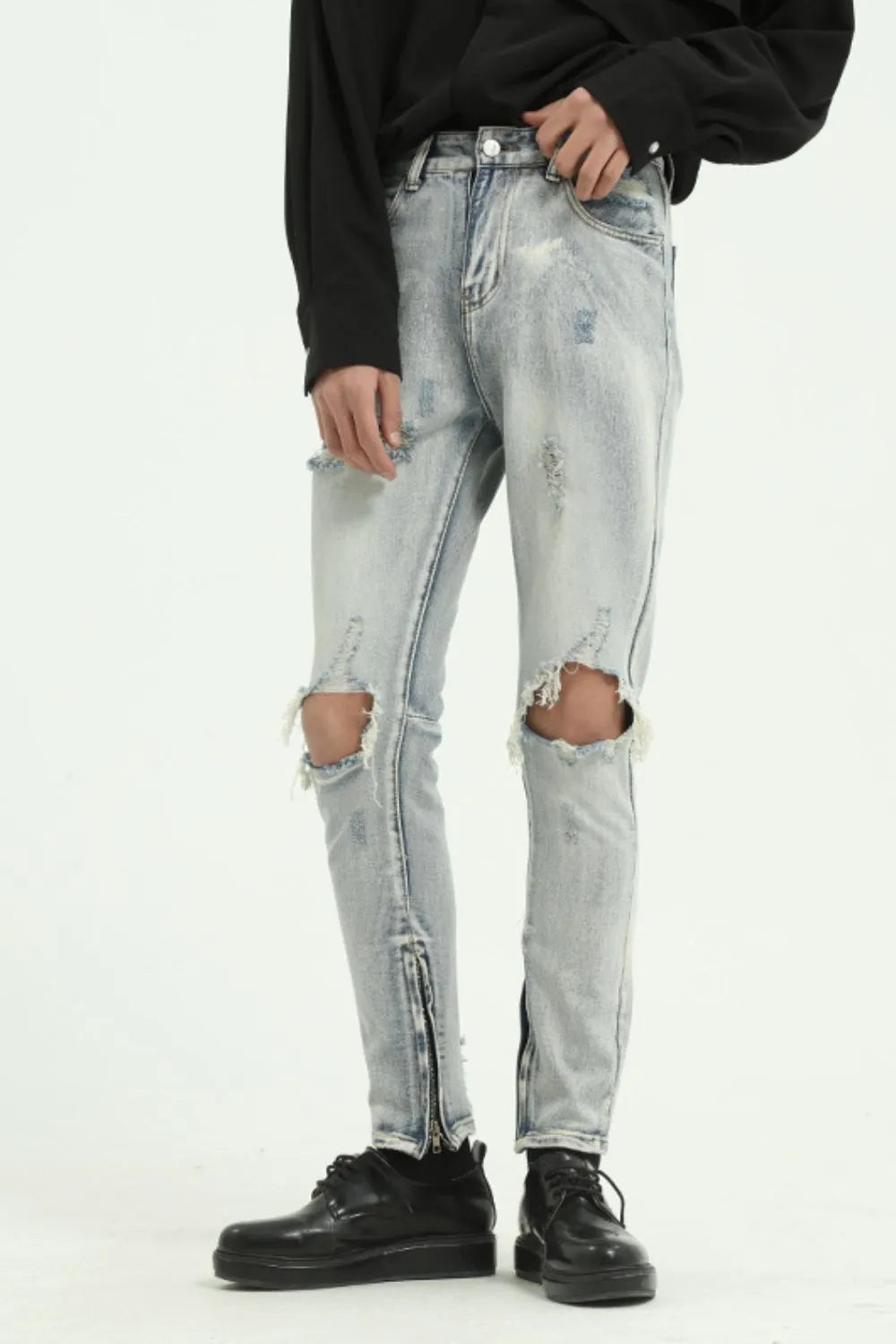 Light wash distressed skinny jeans with ankle zippers and ripped knees.