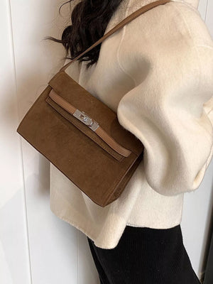 Brown suede shoulder bag with a silver buckle closure and tan strap detail.