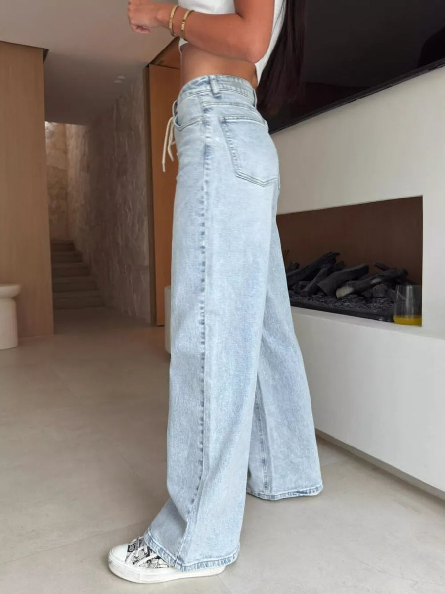 Light wash denim lace-up high-waisted wide leg jeans with a drawstring detail.