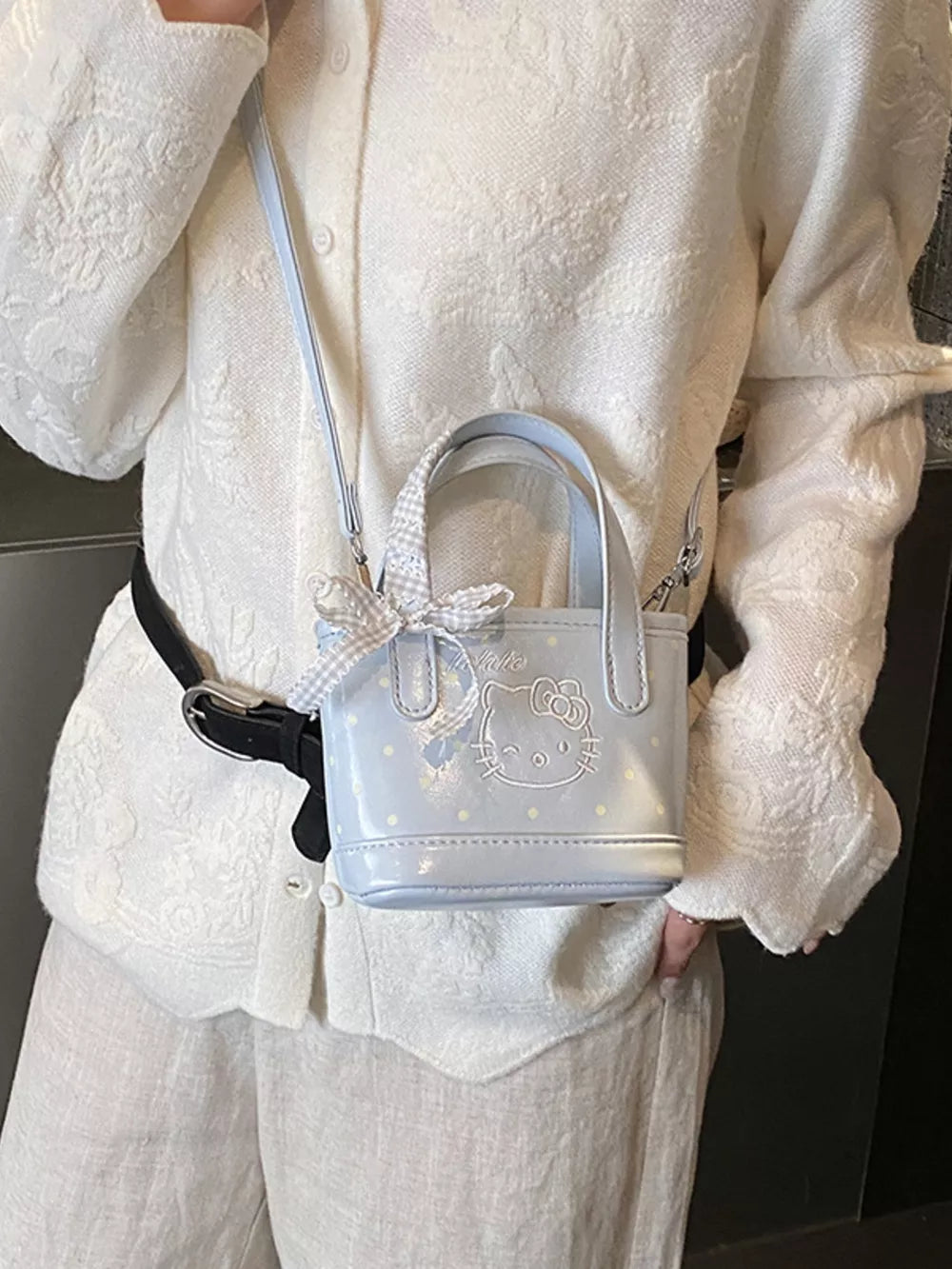Charming mini crossbody bag in light blue with Hello Kitty graphic and bow detail.