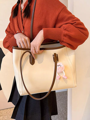 Beige PU leather tote bag with brown trim and a fluffy pink charm.