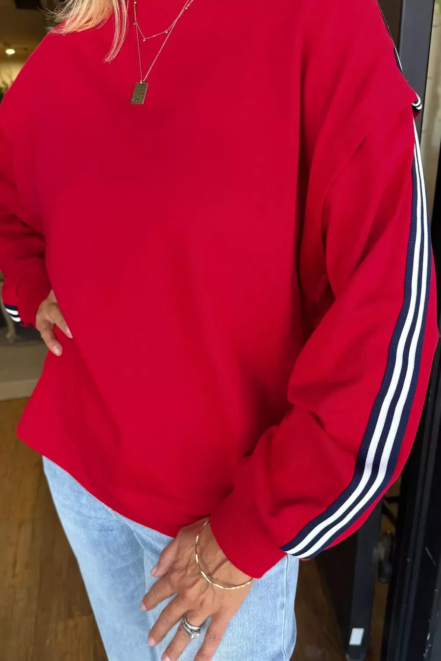 Red sweatshirt with varsity stripe detail on sleeves.