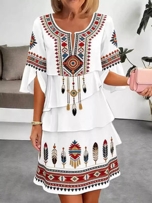 White boho tiered dress with colorful embroidered geometric and feather details, split sleeves.