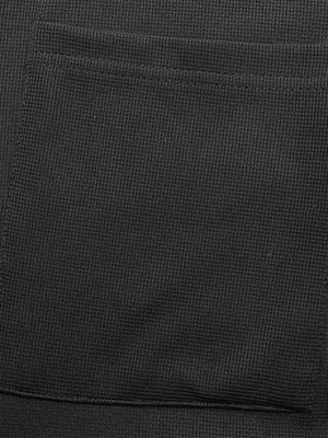 Black textured knit jumpsuit with a visible pocket detail.