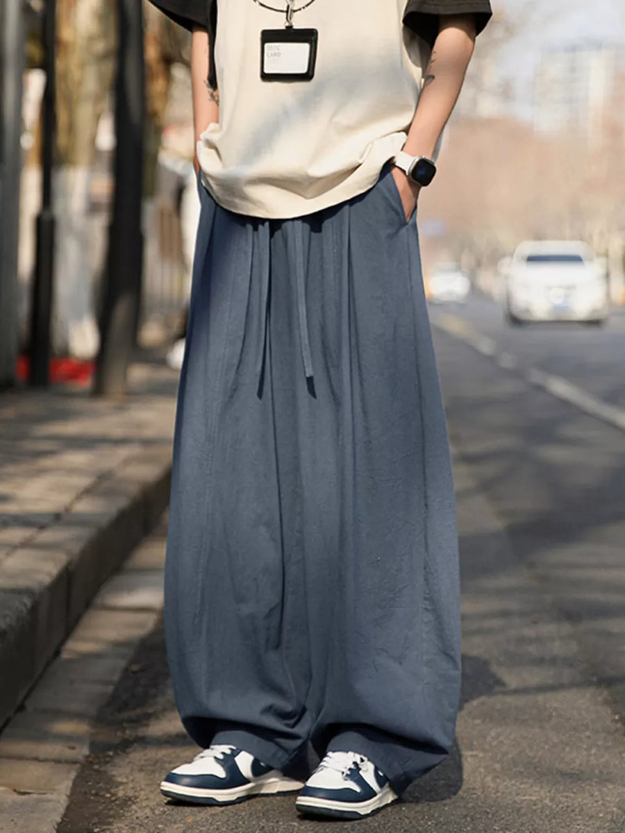 Men's blue wide-leg sweatpants with drawstring and pockets, styled casually.