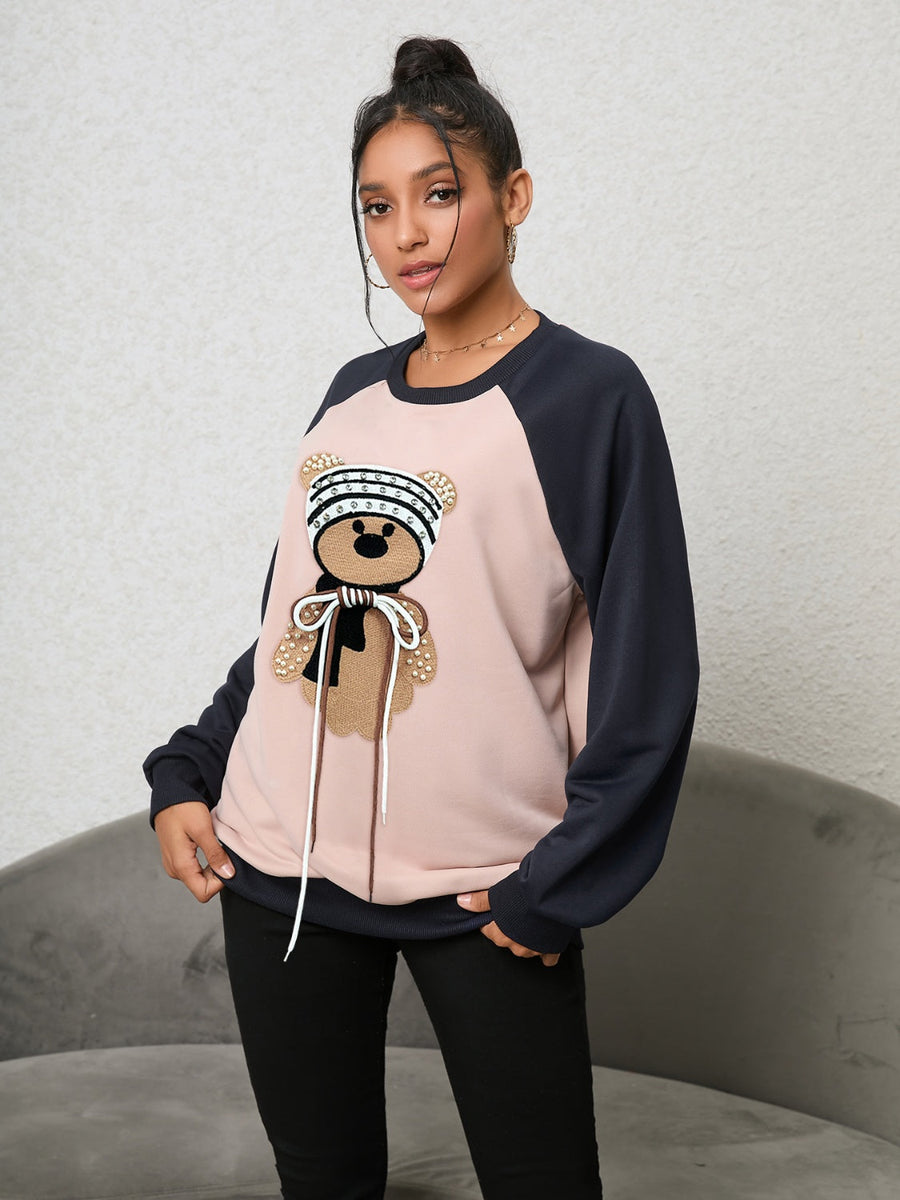 Blush pink raglan sweatshirt with a sequined teddy bear appliqué and drawstring details.