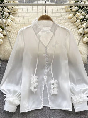 White sheer button-down shirt with delicate floral appliqué and bow details.