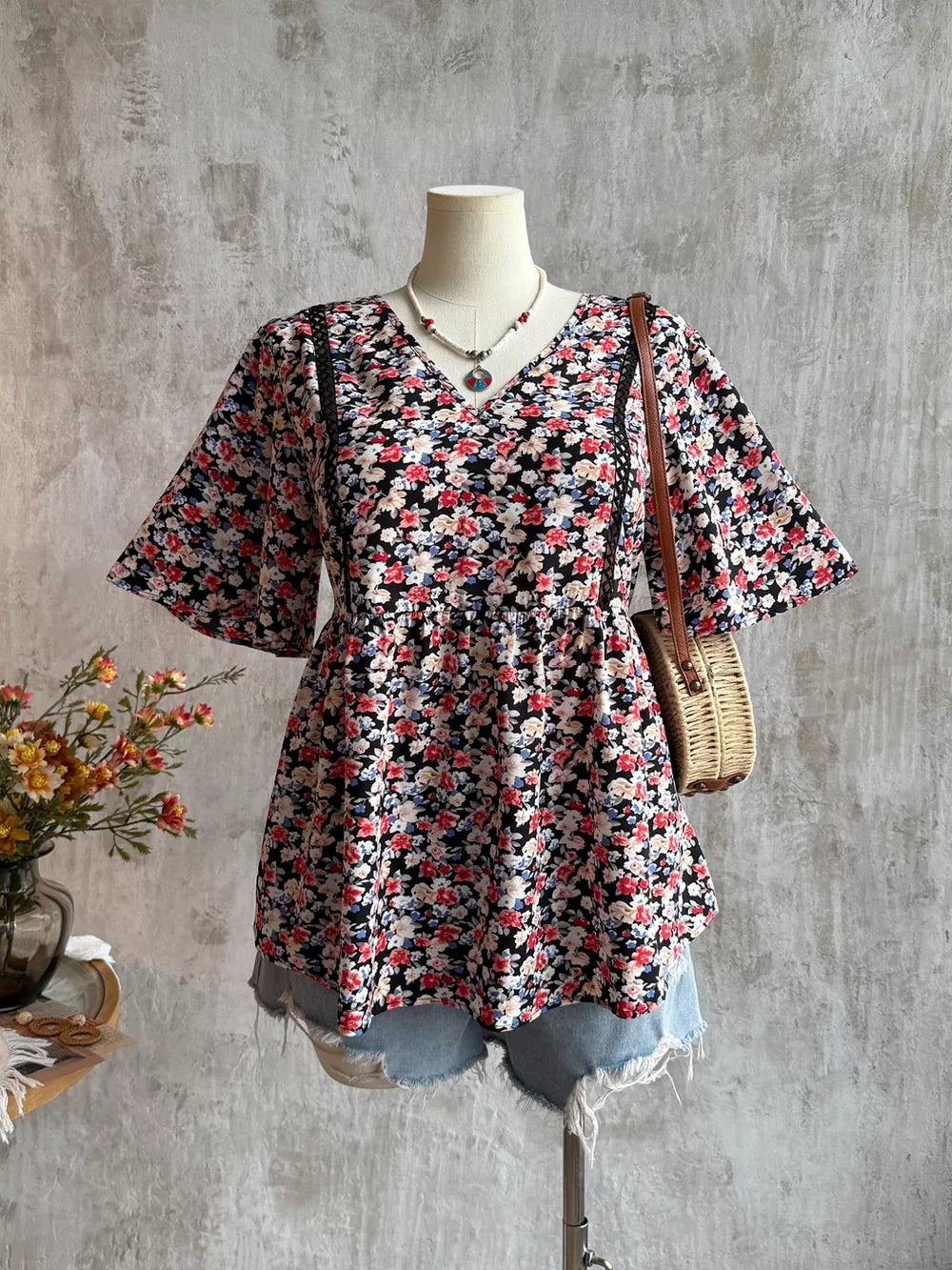 Black floral V-neck blouse with lace trim and flutter sleeves.