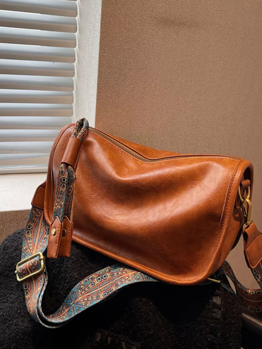 Brown crossbody bag with textured strap and adjustable buckle detail