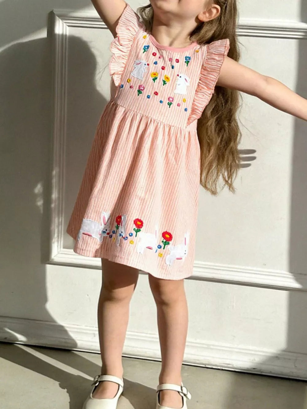 Pink striped cotton dress with embroidered bunnies and flowers, featuring ruffle sleeves.