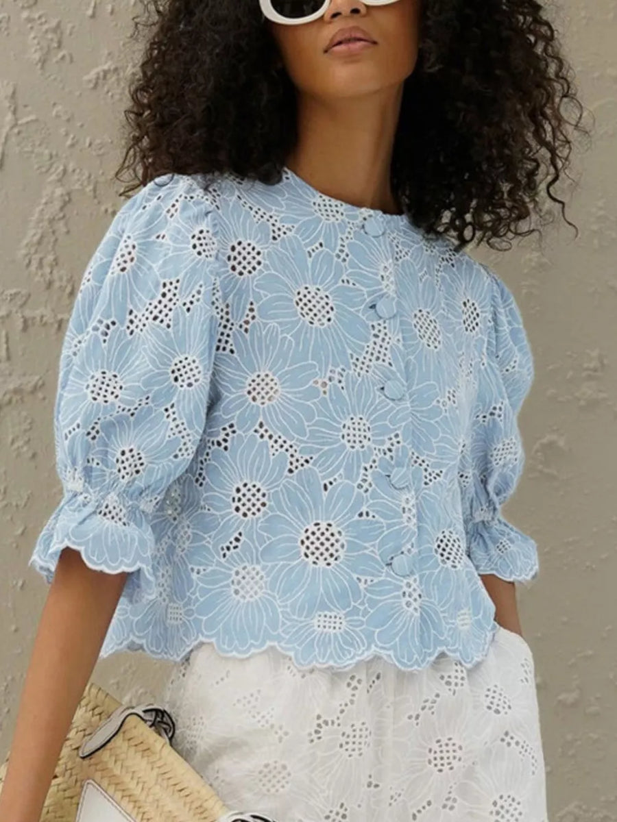 Blue eyelet floral top with puff sleeves and ruffled cuffs.