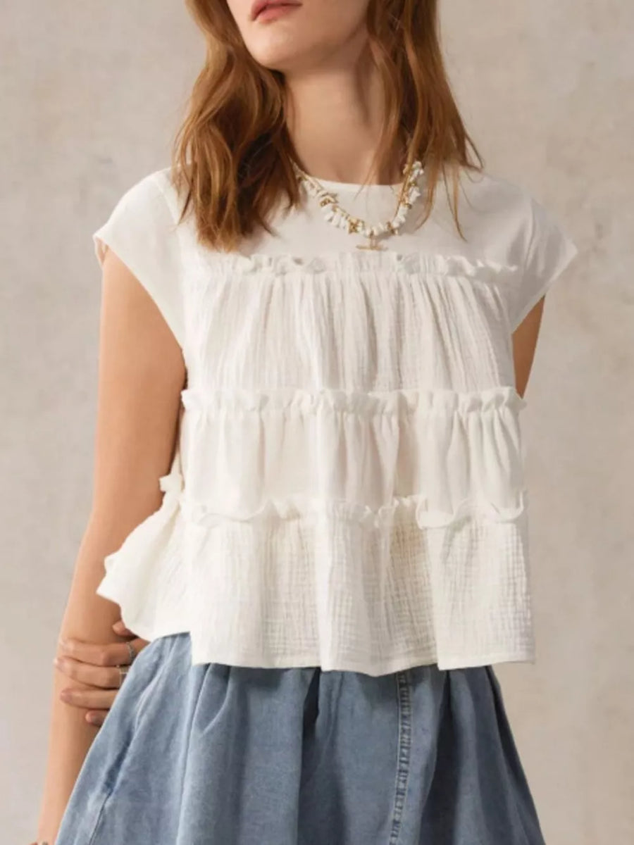 White tiered ruffle blouse with short sleeves and a relaxed fit.