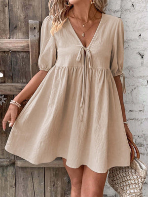 Beige tie front puff sleeve mini dress with adjustable tie details and a v-neckline.