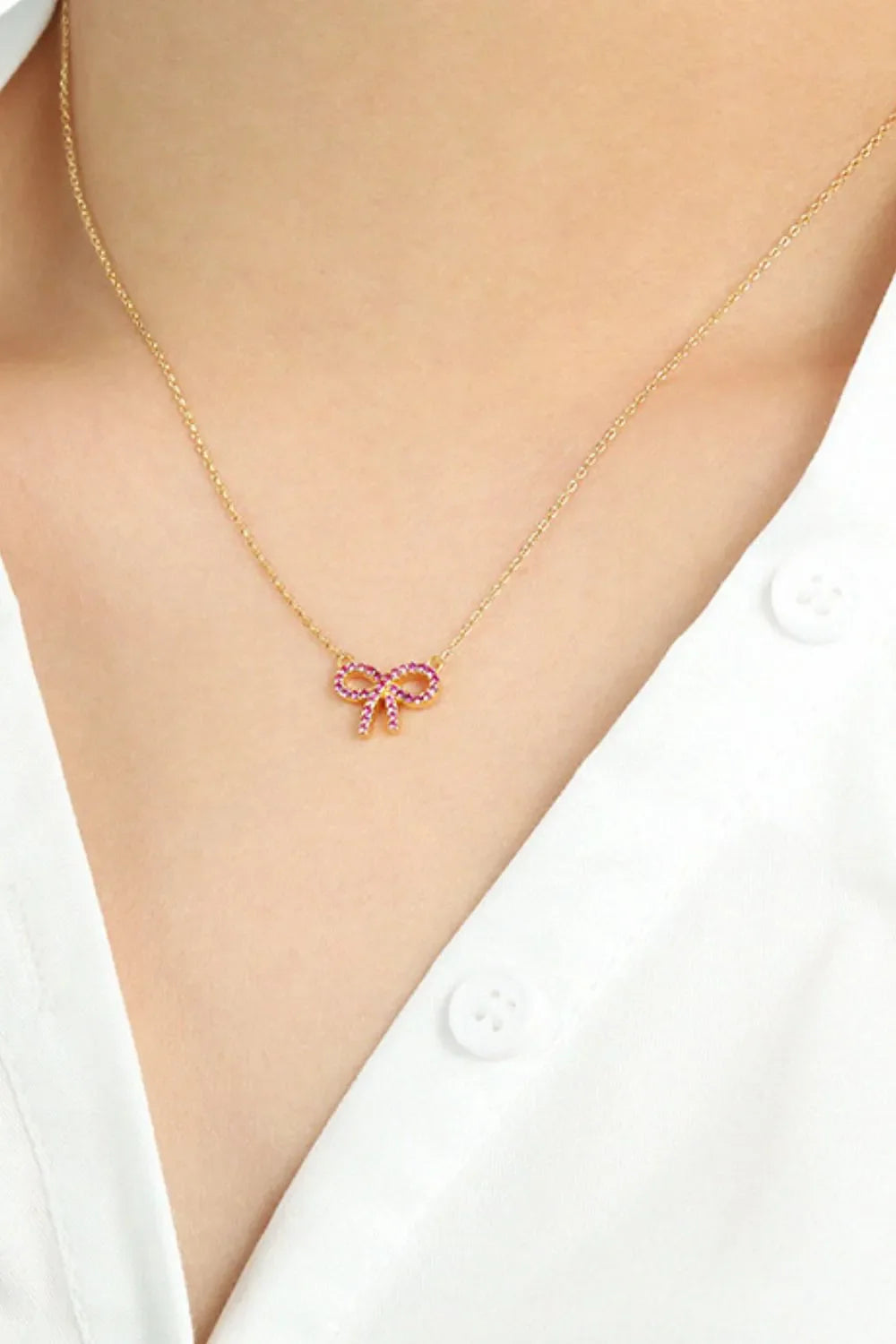 Gold necklace with ruby-embellished bow pendant