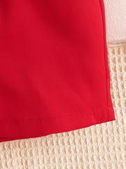 Red baby bodysuit detail with stitched hem and textured background.