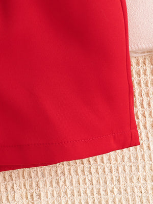 Red baby bodysuit detail with stitched hem and textured background.