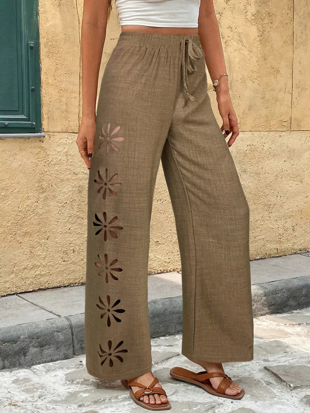 Brown linen wide-leg pants with floral cutouts and drawstring waist.