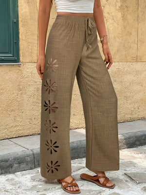 Brown linen wide-leg pants with floral cutouts and drawstring waist.