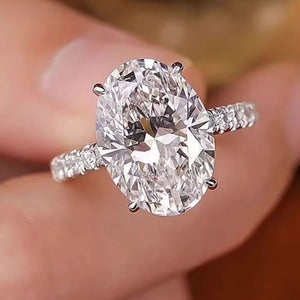 Elegant moissanite oval ring in sterling silver with a pave band.