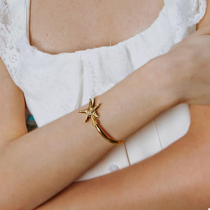 Gold bracelet featuring starfish charm and starfish motif