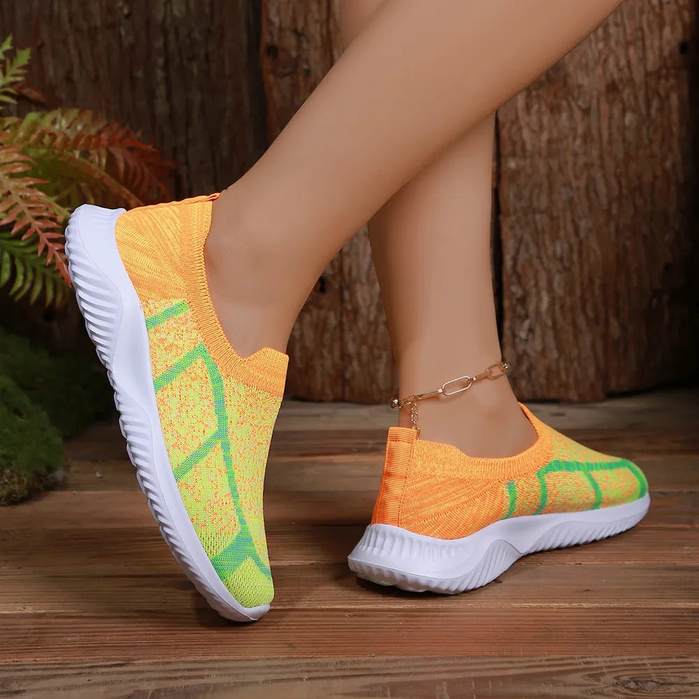 Geometric knit slip-on trainers in orange and yellow with green accents.