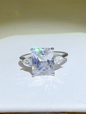 Silver ring with emerald cut center stone and pear accent stones.