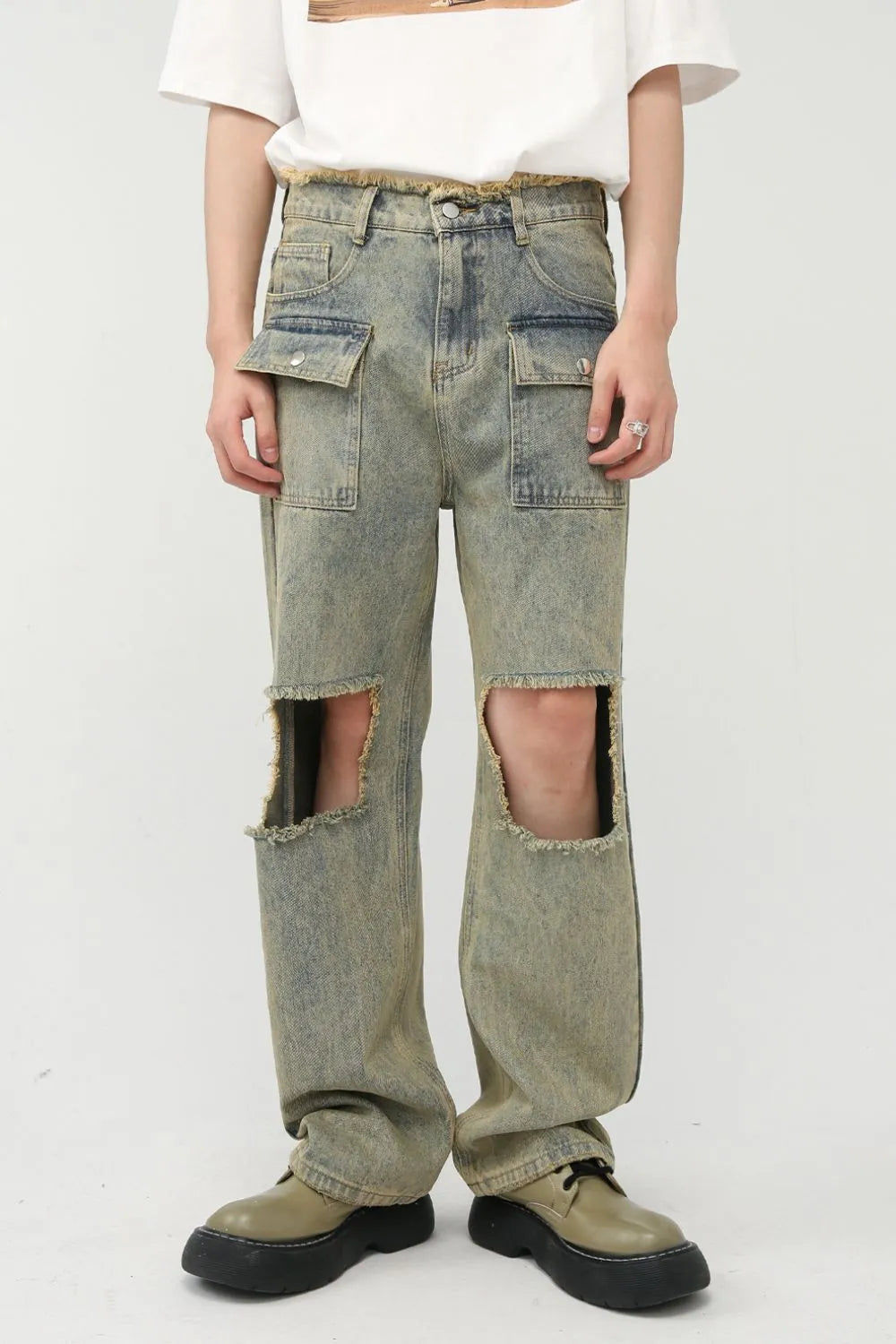 Distressed medium wash denim cargo jeans with cut-outs and raw hem.