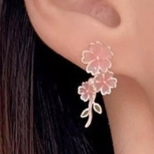 Blush pink floral drop earrings with asymmetrical design and leaf accents.
