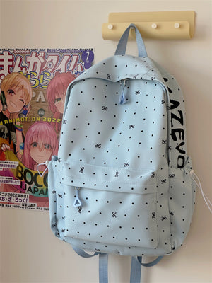 Light blue polka dot backpack with bowknot pattern and front zipper pocket.